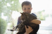 Lächelnder Junge mit Katze im Haus — Stockfoto