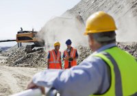 Businessman watching workers in quarry — Stock Photo