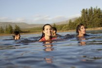 Lächelnde Freunde schwimmen im See — Stockfoto