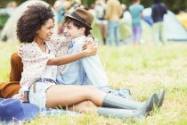 Couple hugging in grass outside tents at music festival — Stock Photo