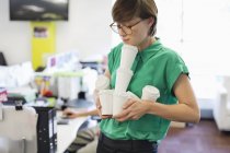 Businesswoman balancing empty coffee cups at modern office — Stock Photo