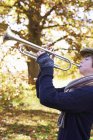 Мальчик-подросток играет на трубе на открытом воздухе — стоковое фото