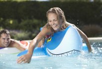 Woman playing on inflatable toy in swimming pool — Stock Photo