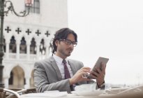 Бизнесмен, использующий цифровой планшет в кафе на тротуаре в Венеции — стоковое фото