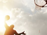Hombre dunking baloncesto en la cancha - foto de stock