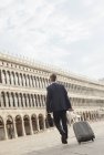Uomo d'affari che tira valigia in Piazza San Marco a Venezia — Foto stock