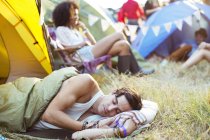 Hombre durmiendo en saco de dormir fuera de la tienda en el festival de música - foto de stock