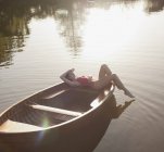 Mujer serena tomando el sol en barco en el lago - foto de stock