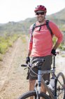 Ciclista de montaña sonriendo en el camino de tierra - foto de stock