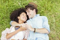 Счастливая пара, держась за руки и лежа в траве — стоковое фото