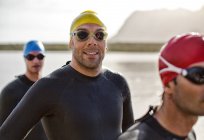 Уверенный и сильный триатлонист в гидрокостюме, улыбающийся в воде — стоковое фото