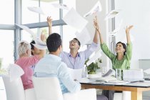 Empresarios lanzando papeles al aire en reunión - foto de stock