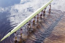 Equipaggio di canottaggio che trasporta scull overhead nel lago — Foto stock