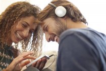Jeune beau couple souriant écoutant des écouteurs — Photo de stock