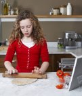 Девочка катит тесто на кухне — стоковое фото