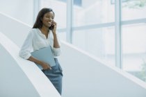 Businesswoman talking on cell phone on office building stairs — Stock Photo