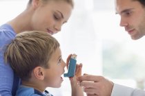 Parents giving son asthma inhaler — Stock Photo