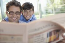 Отец и сын вместе читают газету — стоковое фото