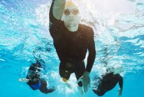 Confident and strong triathletes in wetsuits underwater — Stock Photo