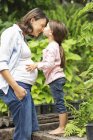 Girl kissing pregnant mother outdoors — Stock Photo
