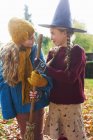 Les filles jouent avec le chapeau et le balai de sorcière à l'extérieur — Photo de stock