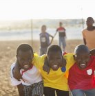 Chicos africanos jugando juntos en el campo de tierra - foto de stock