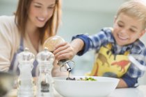 Mother and son making salad in kitchen — Stock Photo