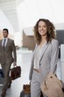 Portrait of smiling businesswoman with suitcase at airport — Stock Photo