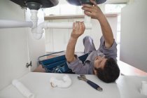 Plumber working on pipes under kitchen sink — Stock Photo