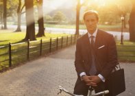Empresário sentado em bicicleta no parque urbano — Fotografia de Stock