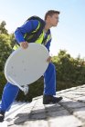 Працівник встановлює супутникову тарілку на даху — стокове фото