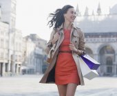 Улыбающаяся женщина с пакетами для покупок гуляет по площади Святого Марка в Венеции — стоковое фото