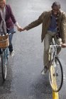 Happy couple holding hands and riding bicycles — Stock Photo
