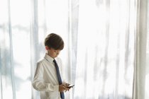Menino de camisa e gravata usando telefone celular — Fotografia de Stock