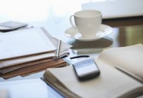 Notebook, cell phone and cup of coffee on desk — Stock Photo