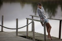Mujer apoyada en barandilla en muelle sobre el lago - foto de stock