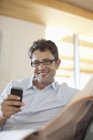 Man using cell phone on sofa — Stock Photo