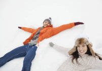 Retrato de pareja feliz haciendo ángeles de nieve - foto de stock