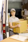 Delivery girl unloading boxes from van — Stock Photo