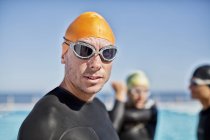 Triatletas confiantes e fortes em fatos de mergulho usando óculos e boné — Fotografia de Stock