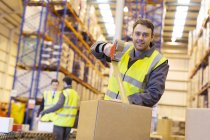 Worker taping cardboard box in warehouse — Stock Photo