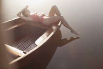 Mujer serena tomando el sol en barco en el lago - foto de stock