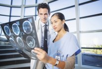Arzt und Krankenschwester betrachten Kopf-Röntgenaufnahmen auf Krankenhaustreppe — Stockfoto