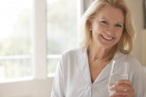 Портрет усміхненої жінки, що п'є склянку води — стокове фото
