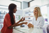 Frau diskutiert in Drogerie mit Apotheker über Hautpflegemittel — Stockfoto