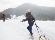 Retrato de mulher sorridente puxando trenó no campo nevado — Fotografia de Stock