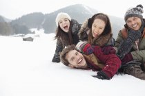 Playful friends laying in snowy field — Stock Photo