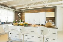Modern kitchen with barstools indoors — Stock Photo