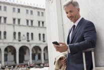 Hombre de negocios mirando hacia abajo en el teléfono celular en Venecia - foto de stock
