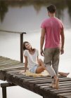 Woman smiling at approaching man on dock over lake — Stock Photo